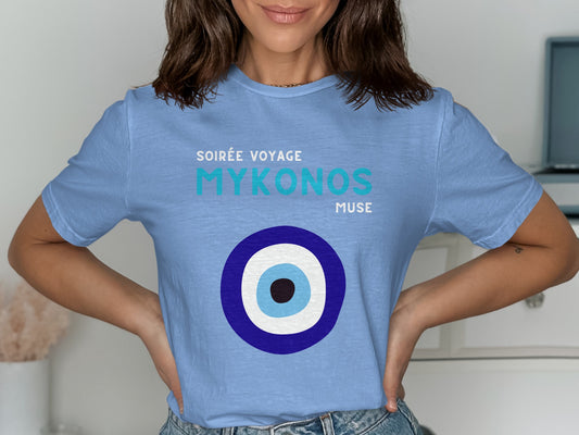 Light blue t-shirt with "Soirée Voyage Mykonos Muse" text and an evil eye graphic.