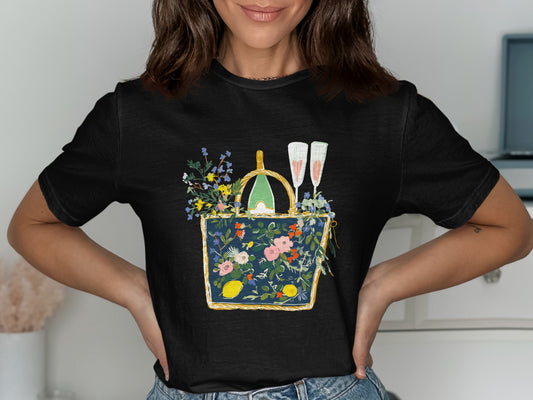 Black t-shirt with a floral picnic basket design featuring champagne and fruit.