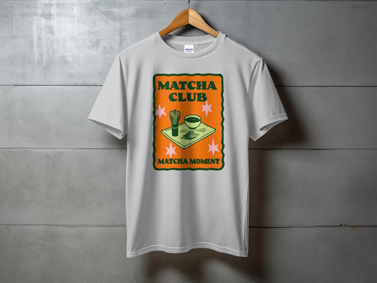 White t-shirt featuring "Matcha Club" and "Matcha Moment" text with matcha bowl and whisk.