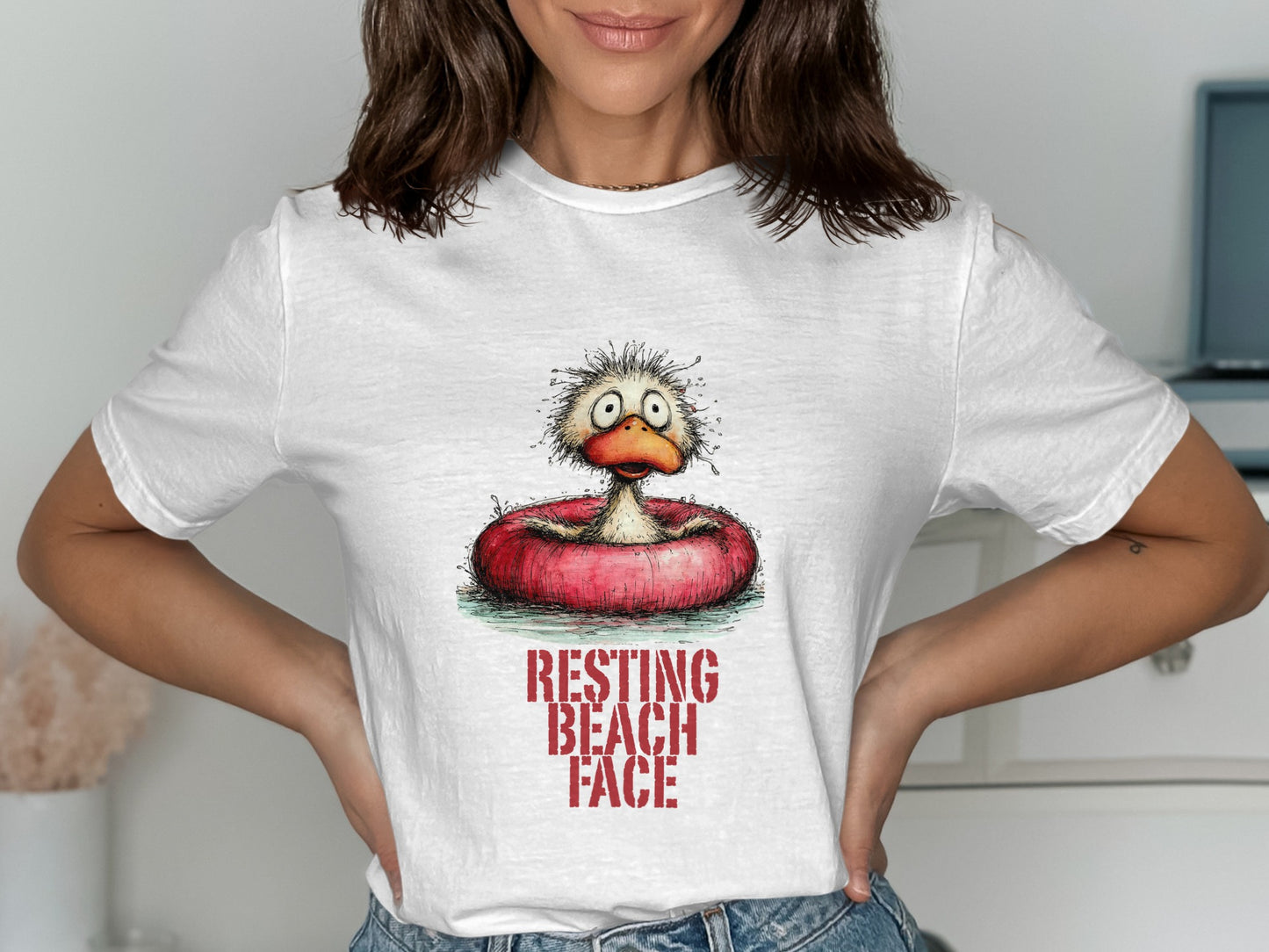 White t-shirt with a cartoon duck in an inner tube, text reads "RESTING BEACH FACE".