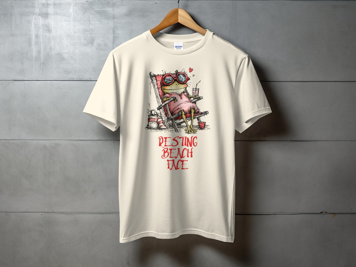 Cream t-shirt with frog in sunglasses on a beach chair, "Pesting Beach Face" text.