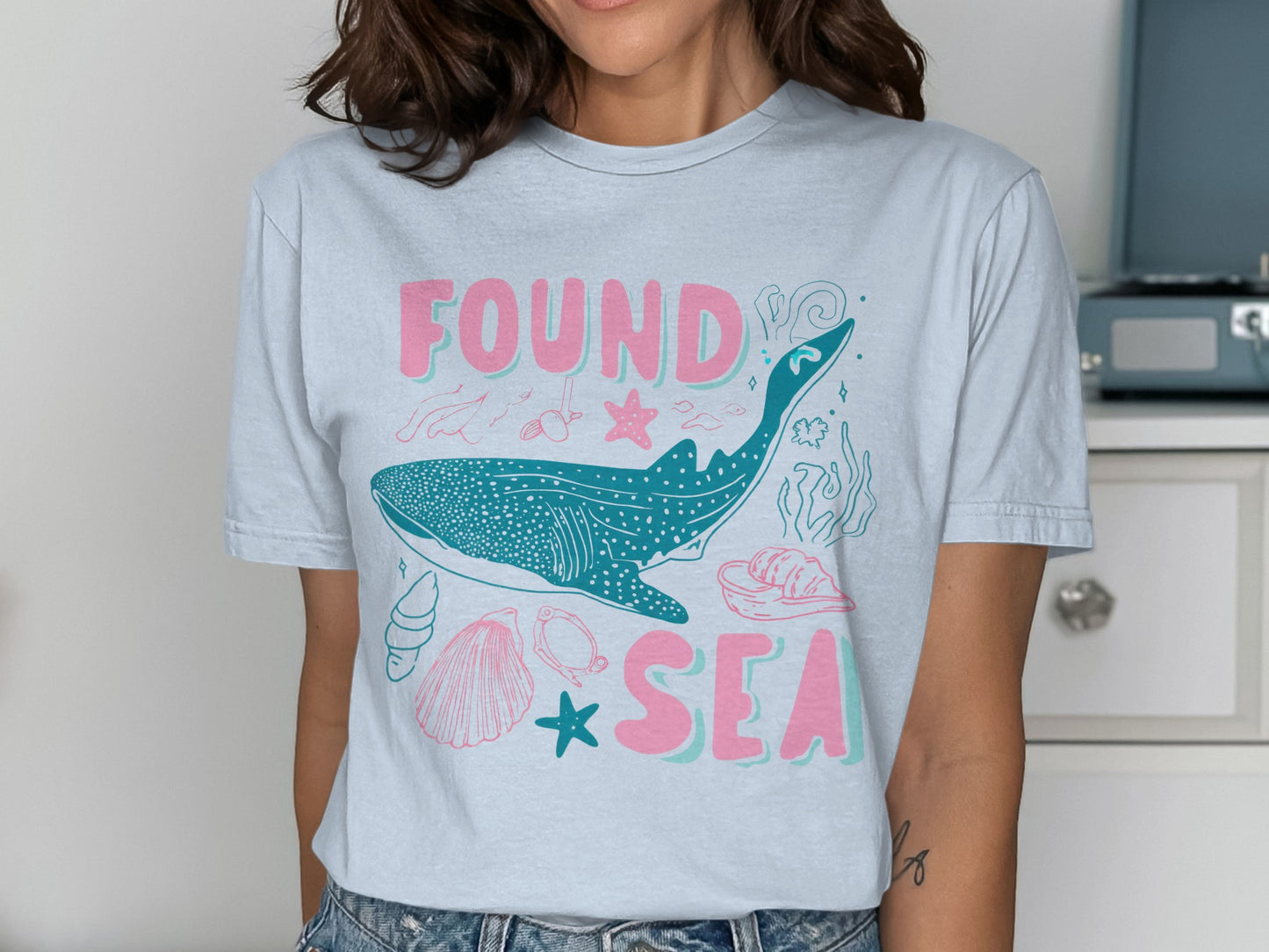 Light blue t-shirt with whale, seashells, and text "FOUND SEA".