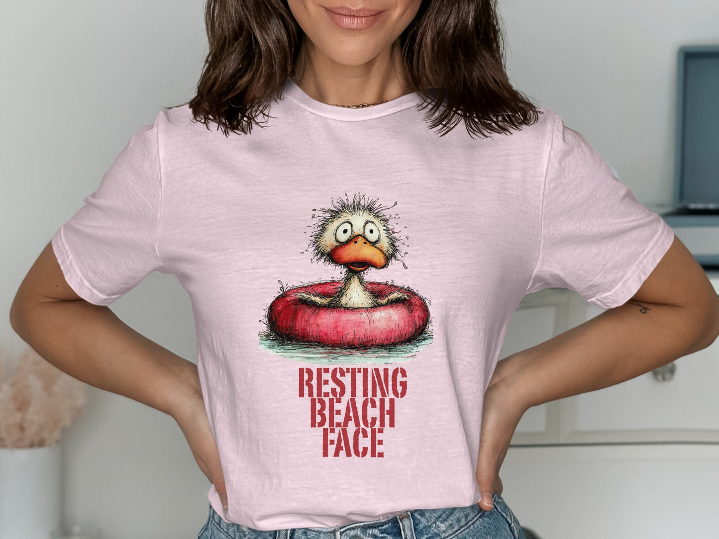Pink t-shirt featuring a cartoon duck in a swim ring with text "RESTING BEACH FACE".