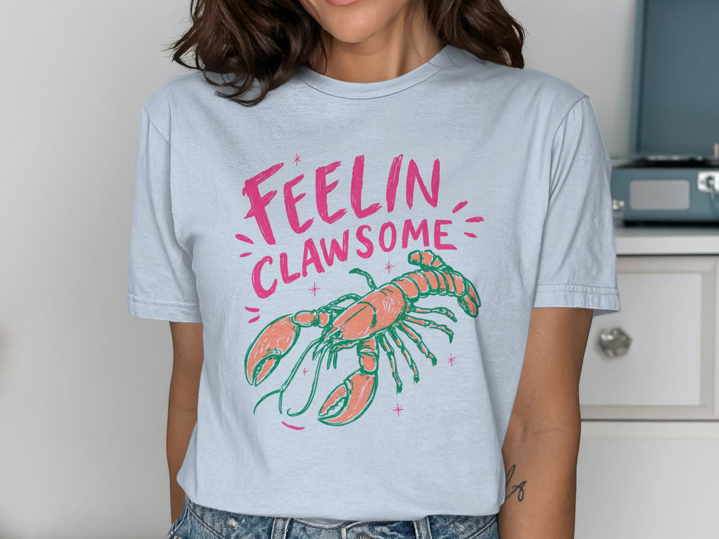 Light blue t-shirt with text "Feelin Clawesome" and a cartoon lobster.