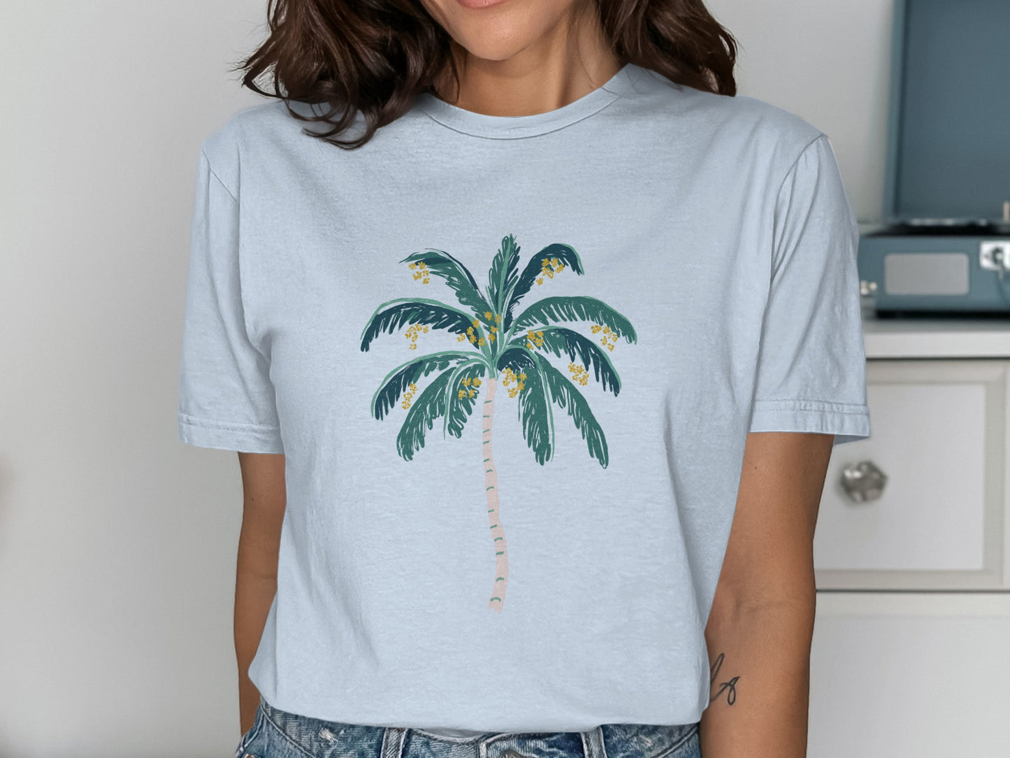Light blue t-shirt with a minimalist palm tree graphic featuring yellow fruit.