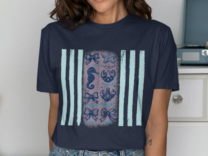 Dark blue t-shirt with light blue stripes and a graphic of various sea creatures and bows.