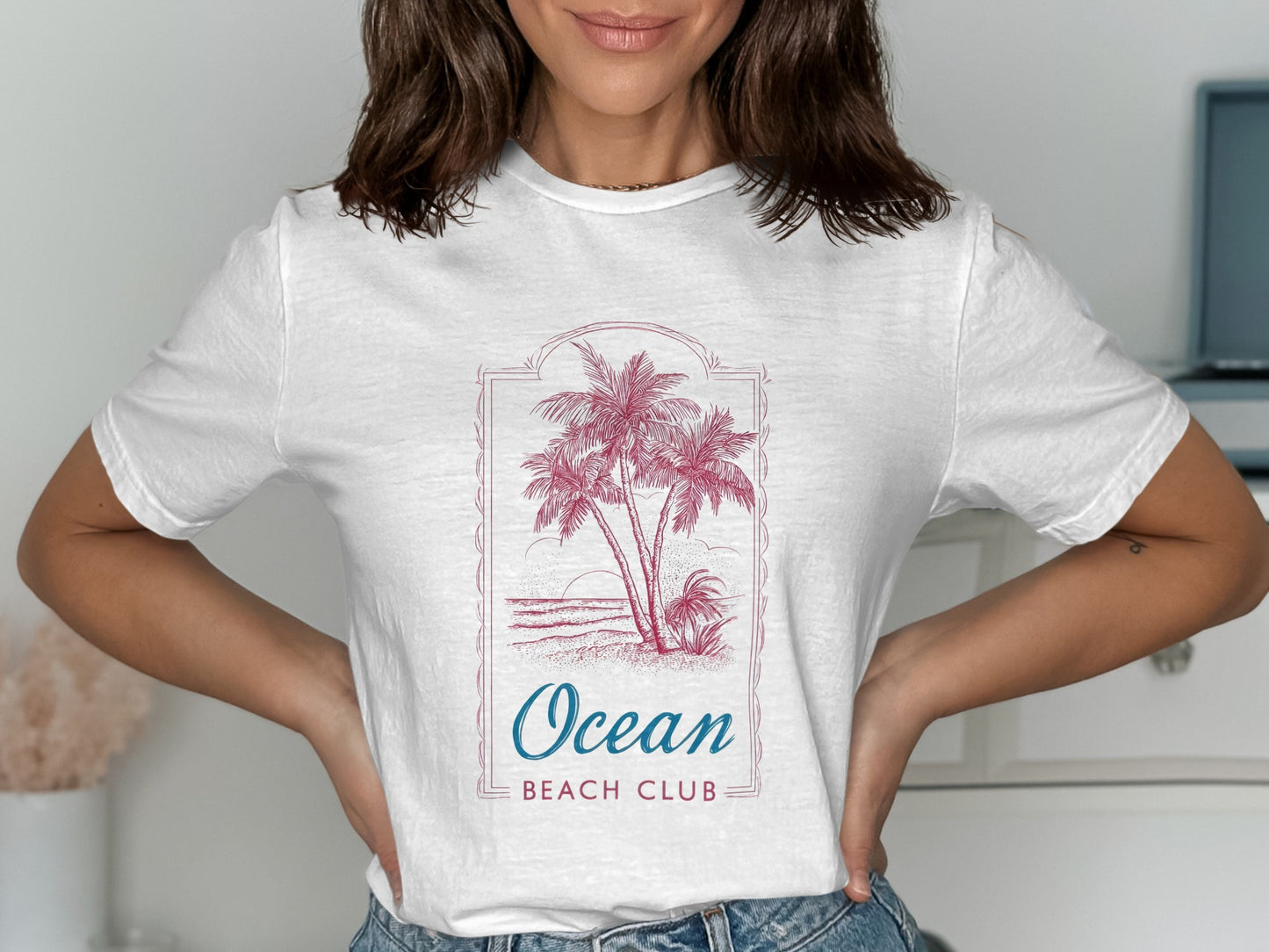 White t-shirt with palm trees, ocean waves, and "Ocean Beach Club" text.