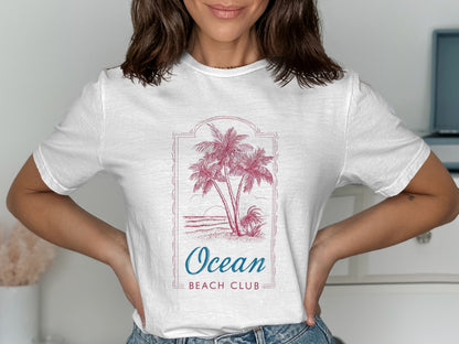 White t-shirt with palm trees, ocean waves, and "Ocean Beach Club" text.