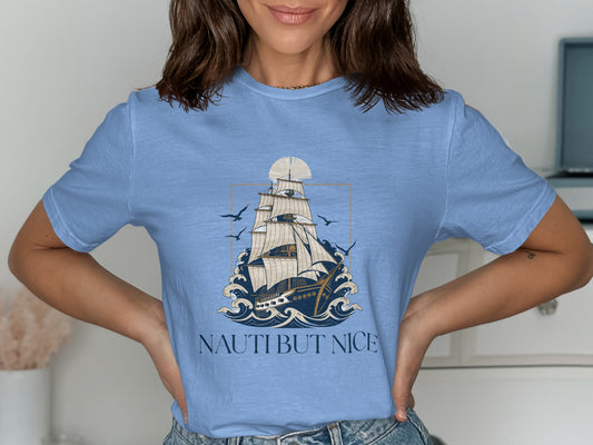 Light blue t-shirt featuring a sailboat on waves and the text "NAUTI BUT NICE".