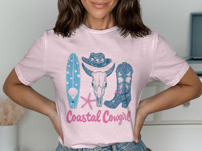 Pink t-shirt with coastal cowgirl graphic: surfboard, skull, cowboy boot, starfish.