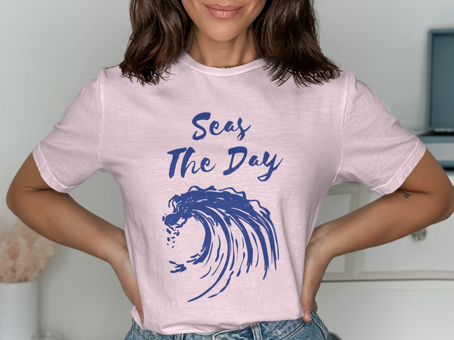 Pink t-shirt with blue wave graphic and "Seas The Day" text.