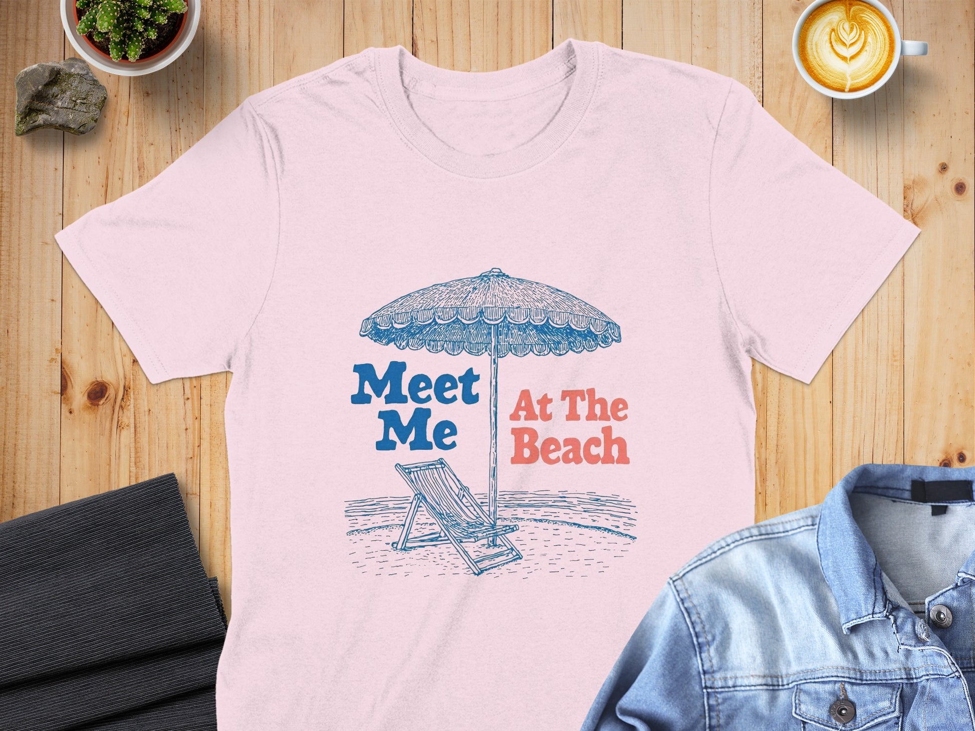 Pink t-shirt with "Meet Me At The Beach" text and beach scene graphic.