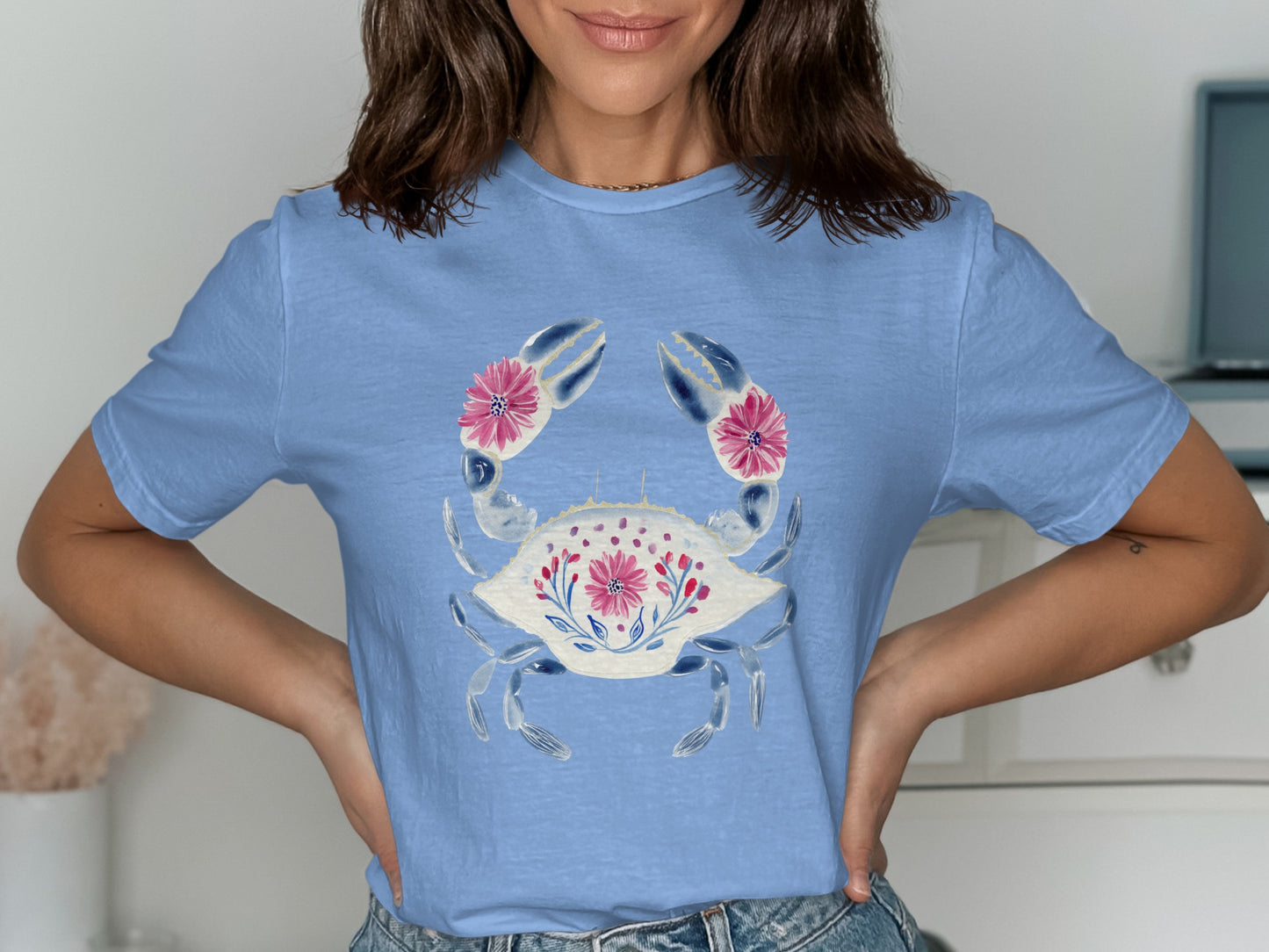 Light blue t-shirt featuring a stylized crab with pink floral accents.
