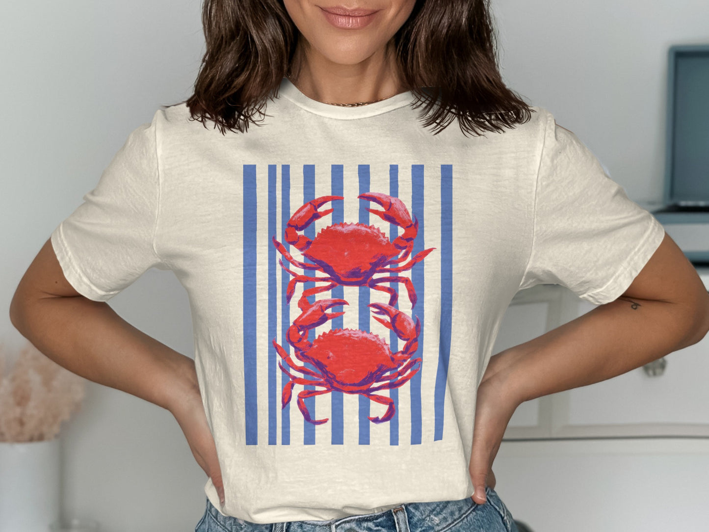 Cream t-shirt with two red crabs on a blue striped background.