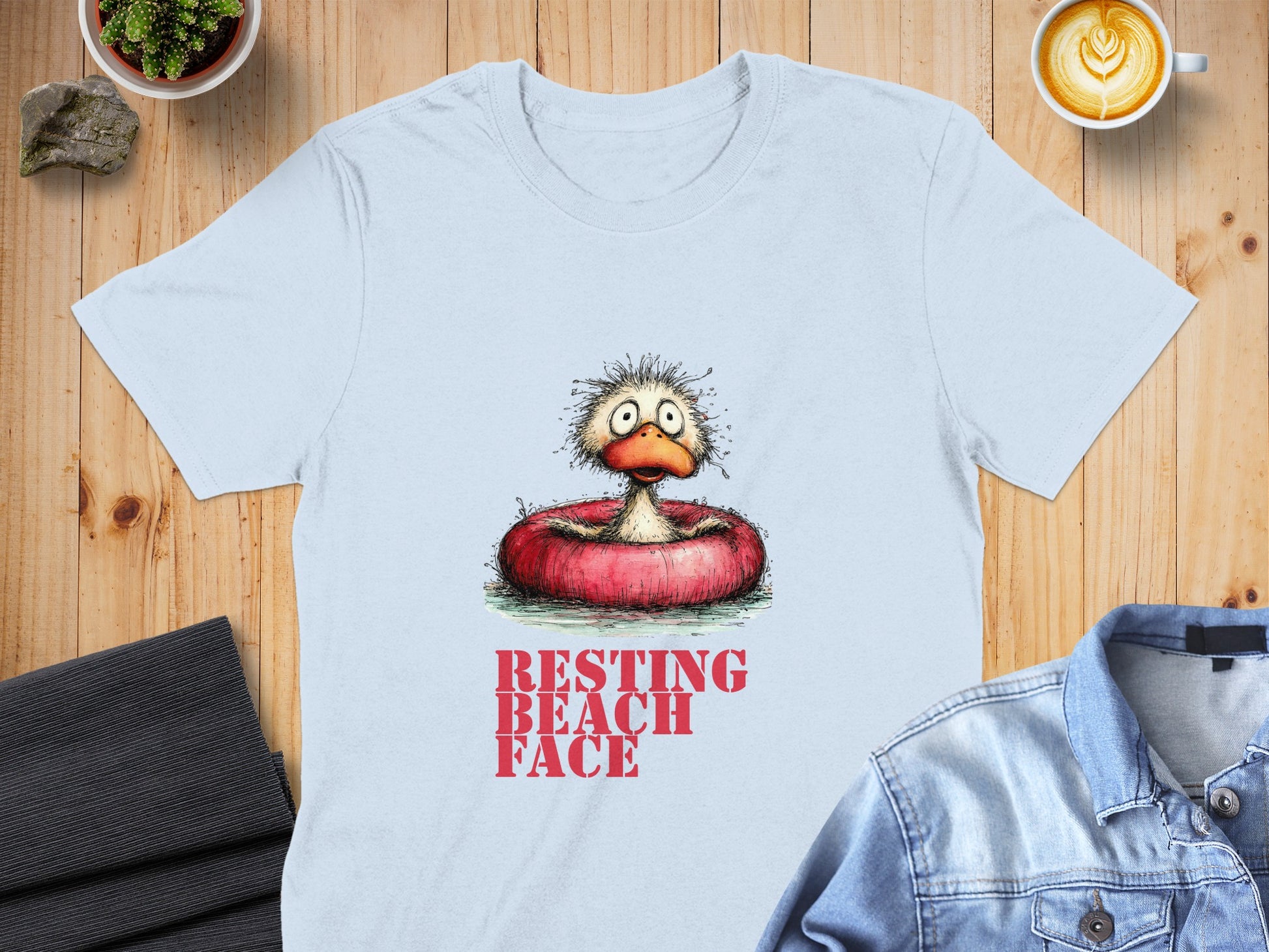 Light blue t-shirt with distressed "RESTING BEACH FACE" text and cartoon duck in inner tube.