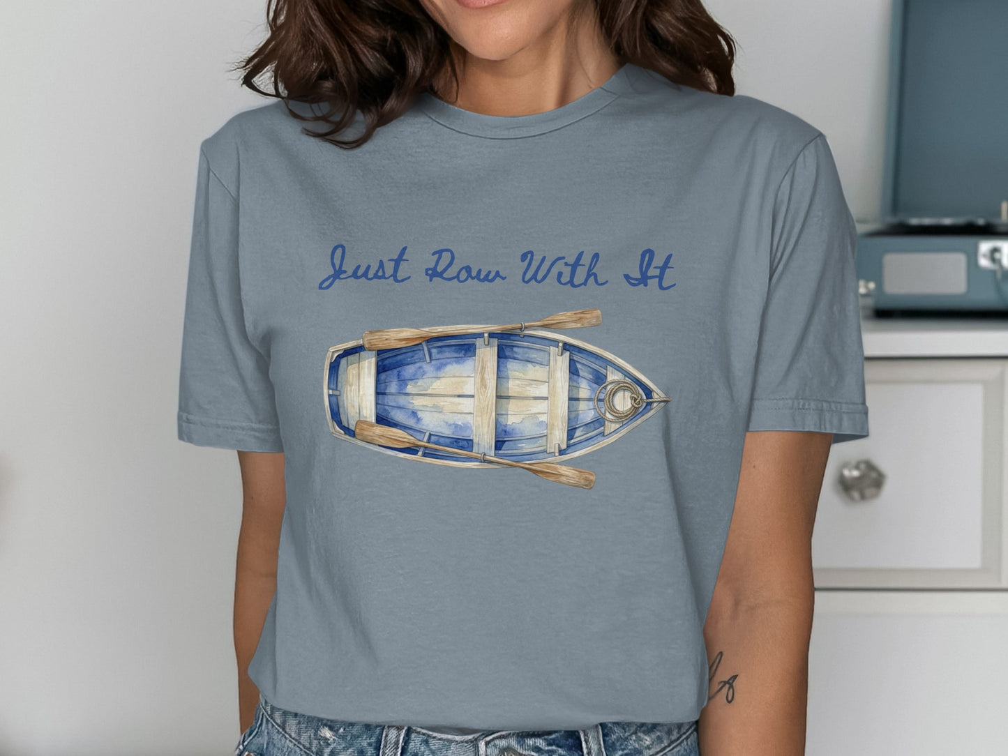 T-shirt with blue watercolor rowboat and oars, text "Just Row With It".