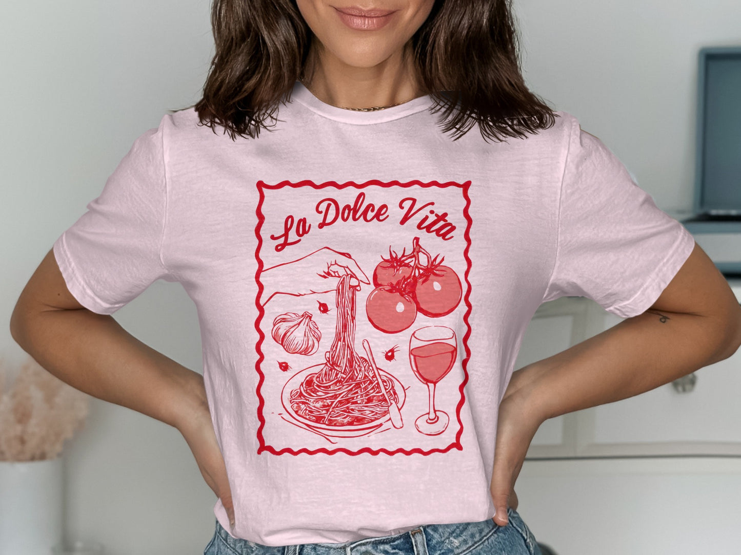 Pink t-shirt with "La Dolce Vita" text and spaghetti, tomatoes, garlic, and wine illustration.