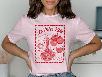 Pink t-shirt with "La Dolce Vita" text and spaghetti, tomatoes, garlic, and wine illustration.