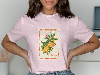 Pink t-shirt with a framed illustration of oranges and floral accents.
