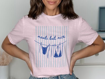 Pink t-shirt with "nauti but nice" and bikinis hanging on a clothesline.