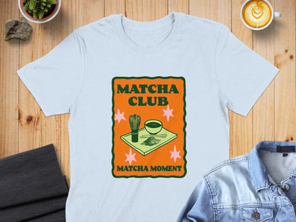 Light blue t-shirt with "Matcha Club Matcha Moment" graphic and matcha tea set.