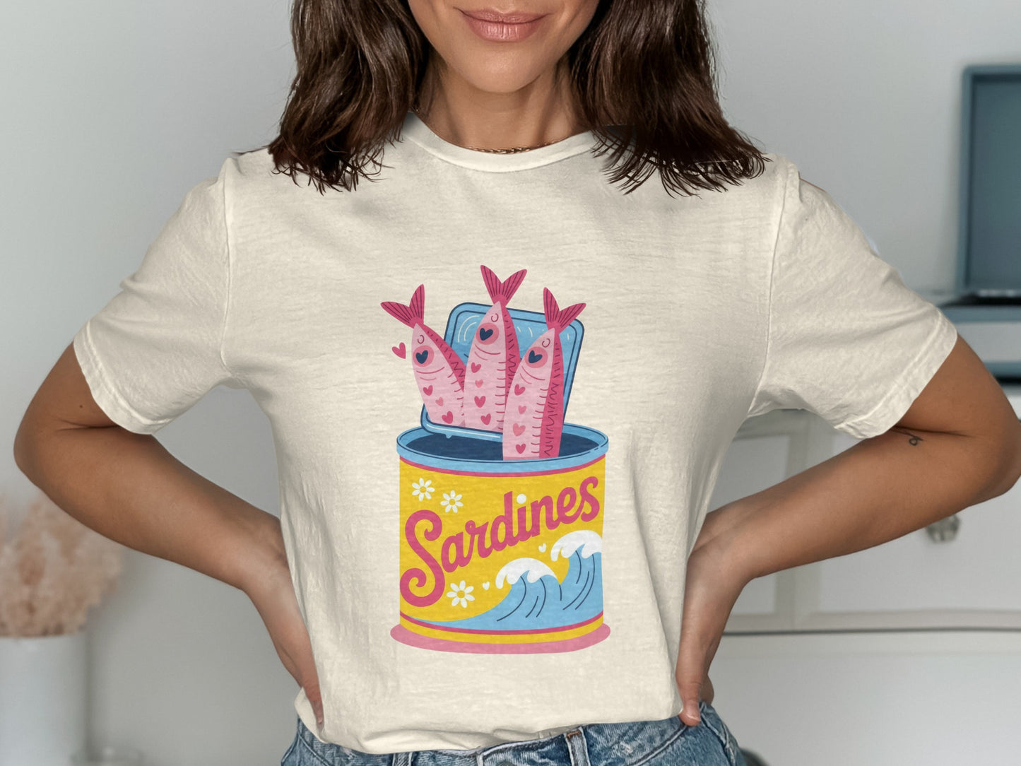 Cream t-shirt featuring a graphic of a sardine can with three smiling fish.