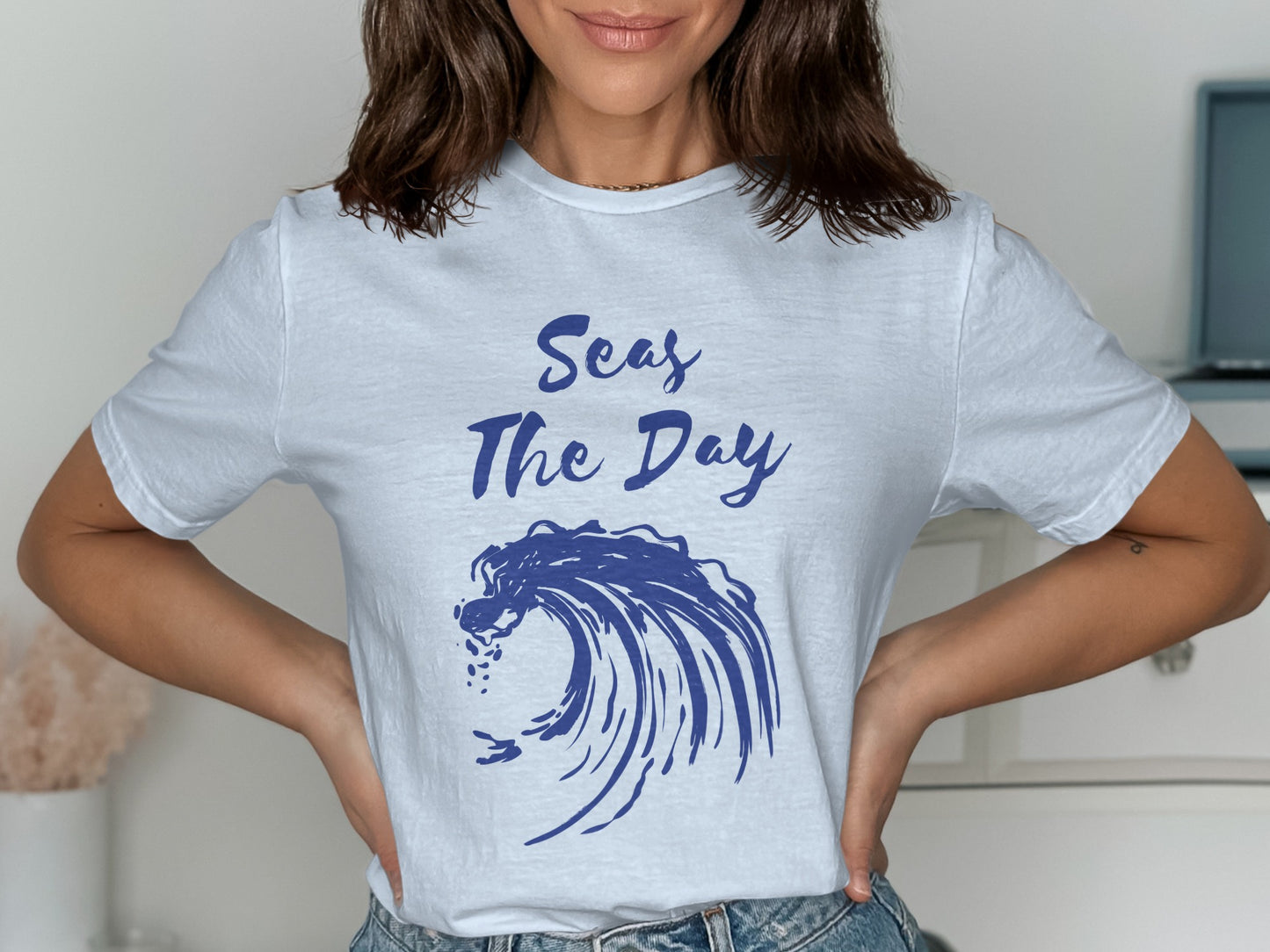 White t-shirt with blue wave graphic and text "Seas The Day".