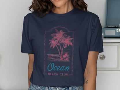 Navy t-shirt with pink palm trees, sunset, and "Ocean Beach Club" text.