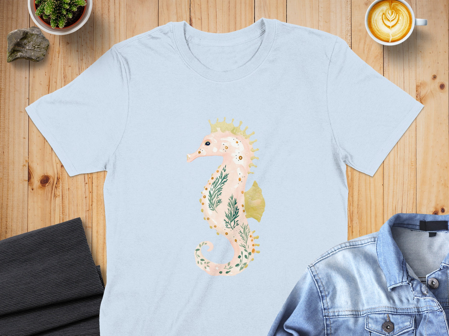 Light blue t-shirt with a pastel seahorse illustration featuring floral and crown details.
