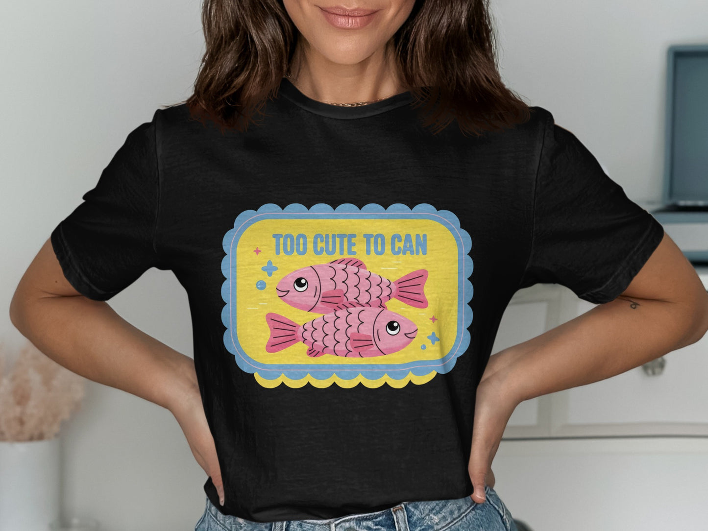 Black t-shirt with cartoon fish graphic and text "TOO CUTE TO CAN".