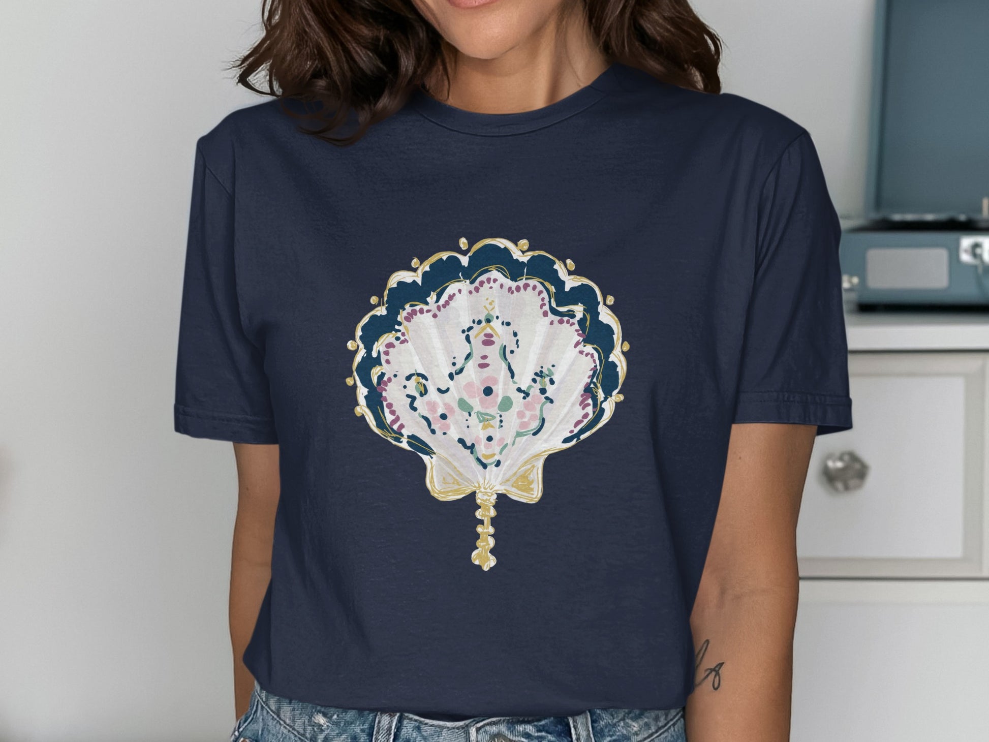 Navy t-shirt with a decorative seashell design featuring gold and floral accents.