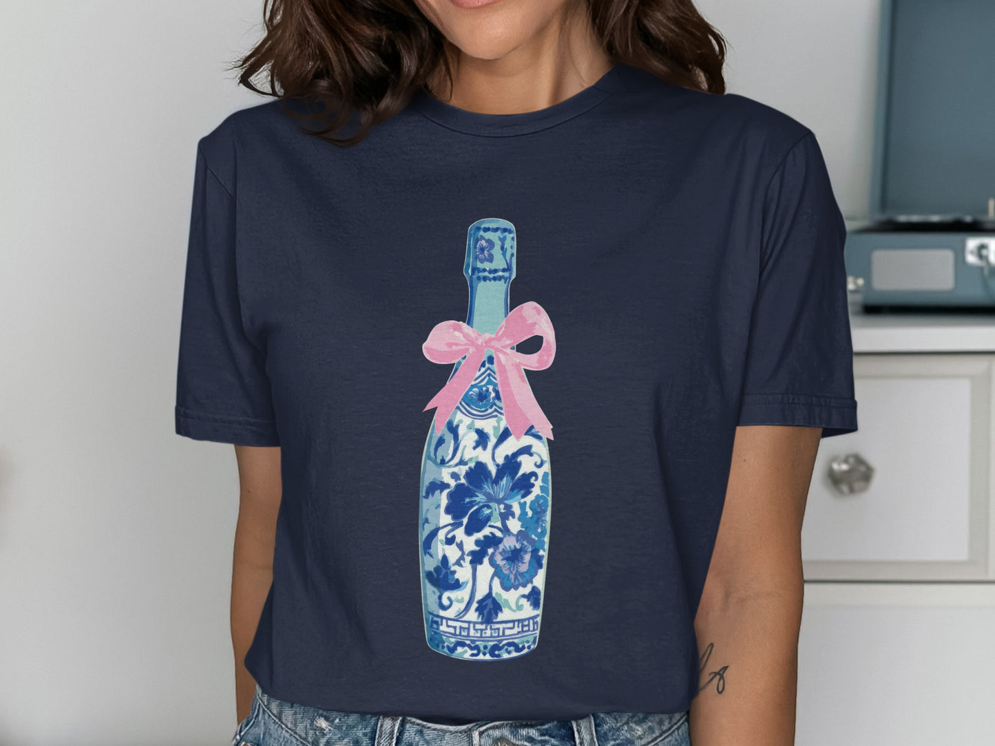 Navy t-shirt with a blue and white floral patterned bottle and pink bow.