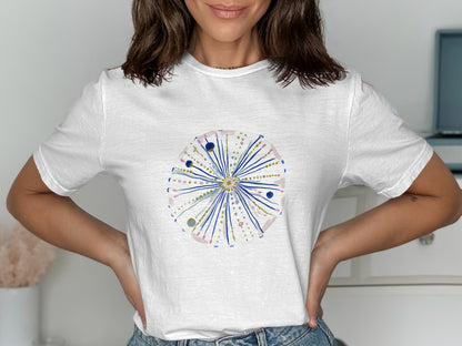 White t-shirt with a circular, starburst-like design in pink, blue, and gold.