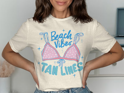 Cream t-shirt with "Beach Vibes Tan Lines" graphic featuring a pink polka dot bikini top.