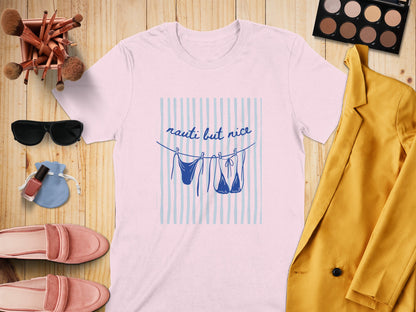 Pink t-shirt with "nauti but nice" text and two hanging swimsuits.