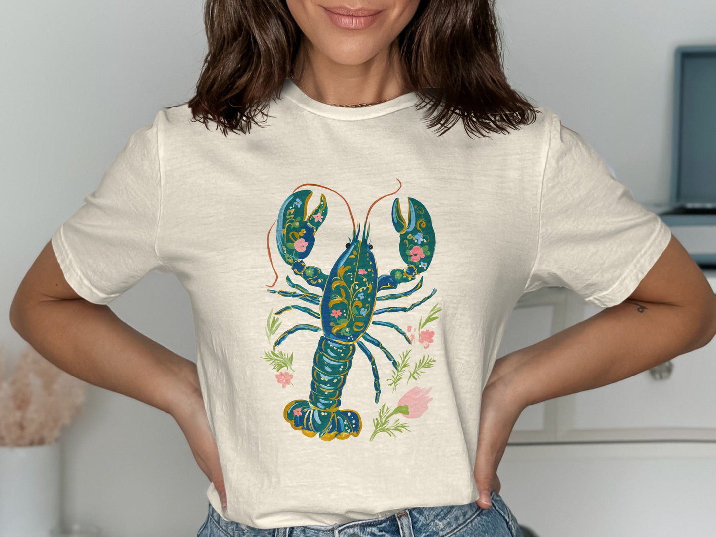 Cream t-shirt with ornate blue lobster and pink floral design.