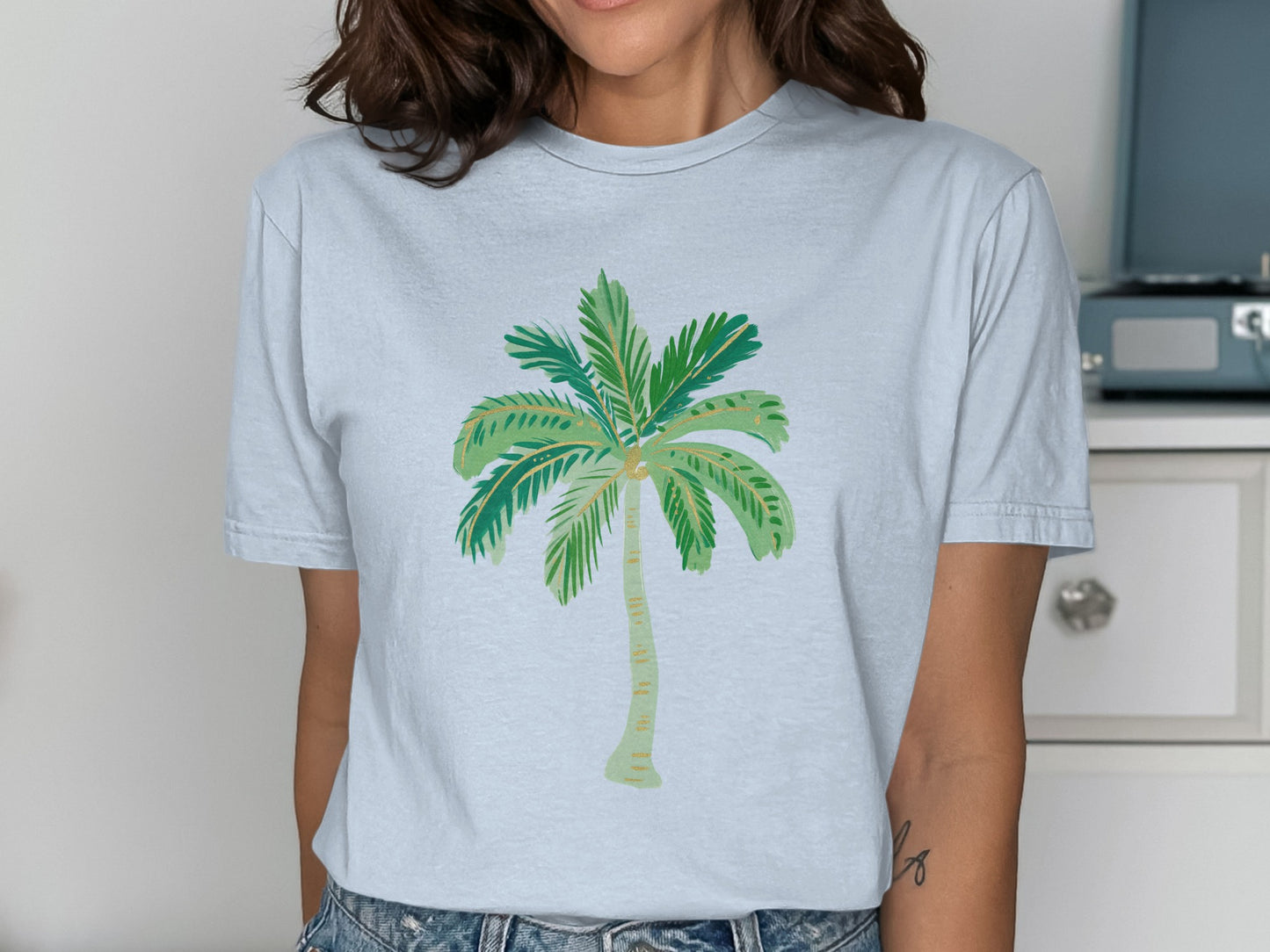 Light blue t-shirt with a stylized green palm tree graphic.