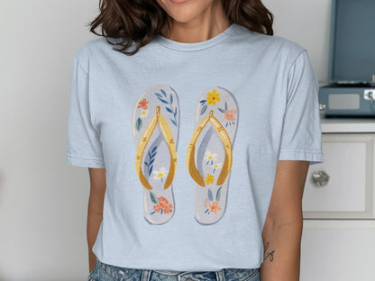 Light blue t-shirt with a graphic of two floral flip-flops.