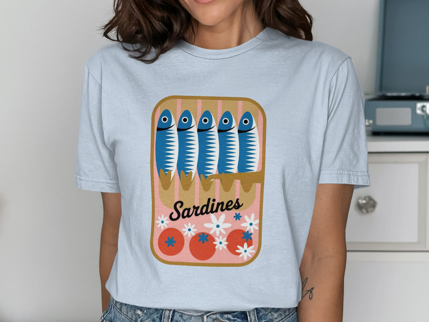 T-shirt featuring a stylized illustration of a sardine can with fish and flowers.