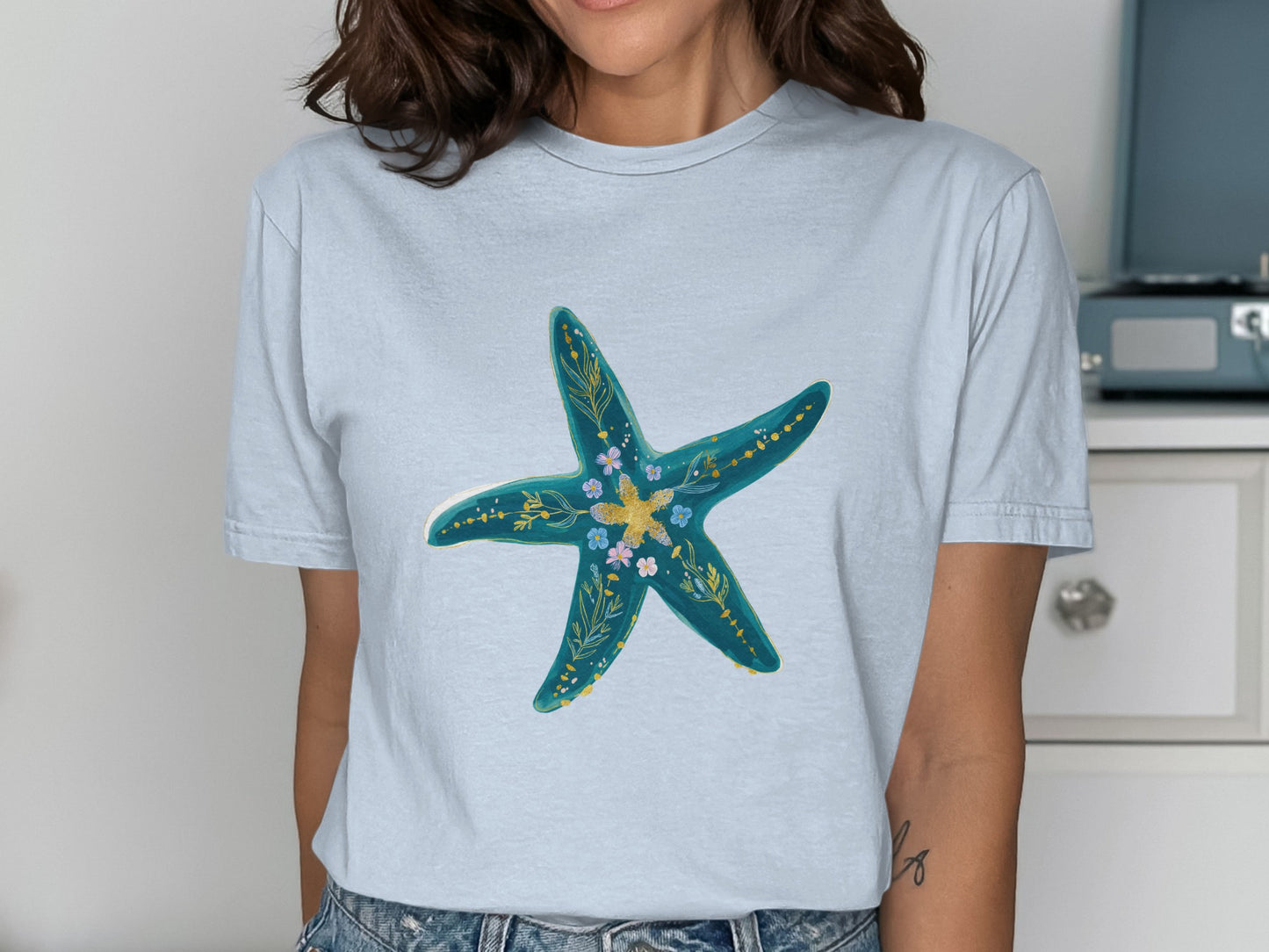 Light blue t-shirt with a turquoise starfish design featuring floral accents.