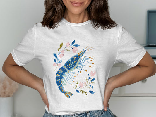 White t-shirt featuring a blue shrimp with floral accents.