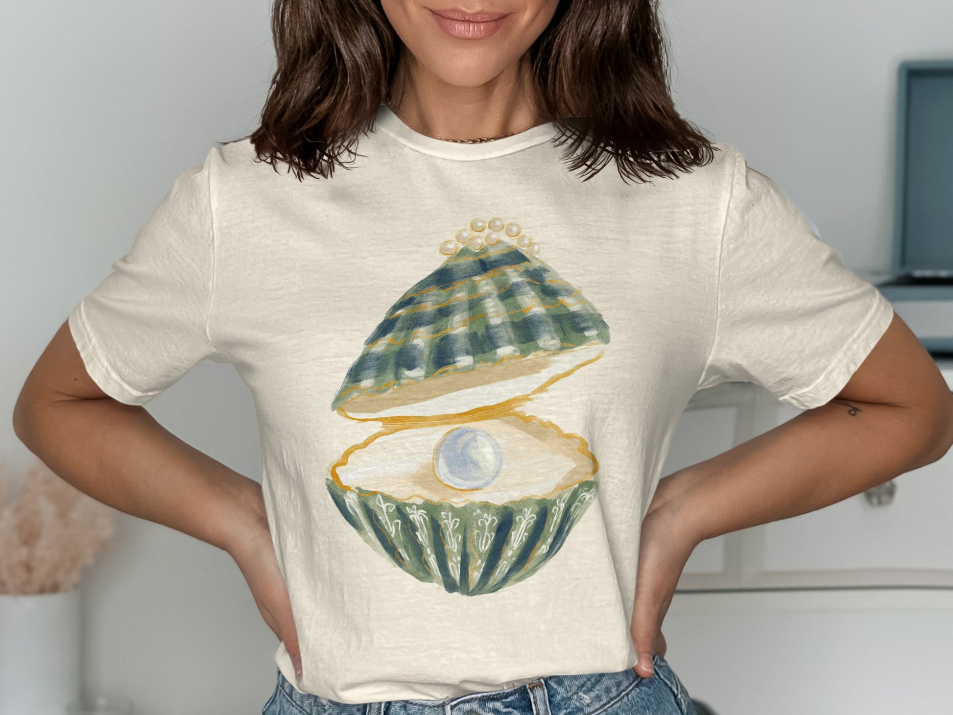 Cream t-shirt with a graphic of an open oyster holding a pearl.