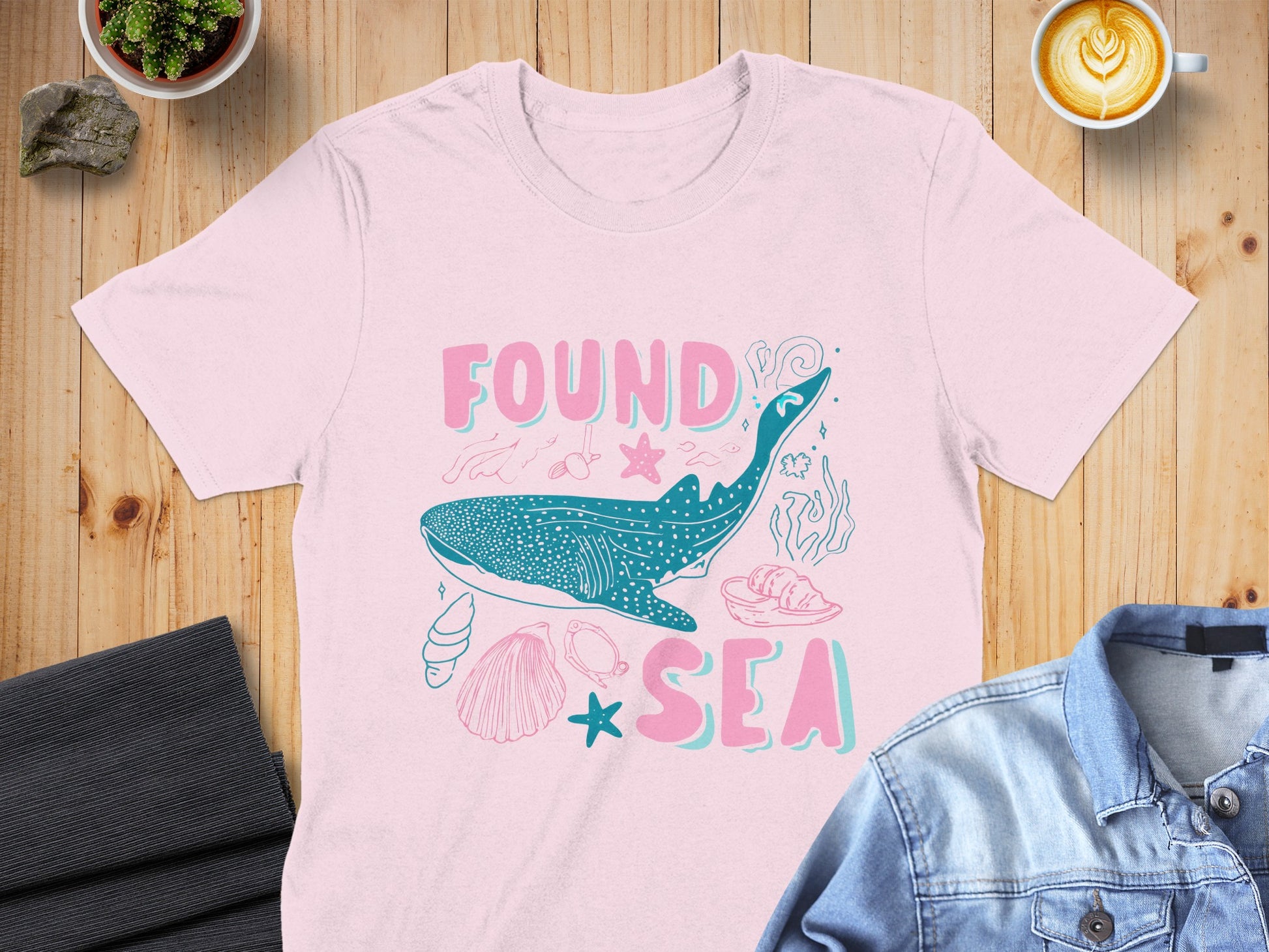 Pink t-shirt with "FOUND SEA" text and whale shark illustration.