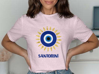 Pink t-shirt with a blue and gold evil eye design and "SANTORINI" text.