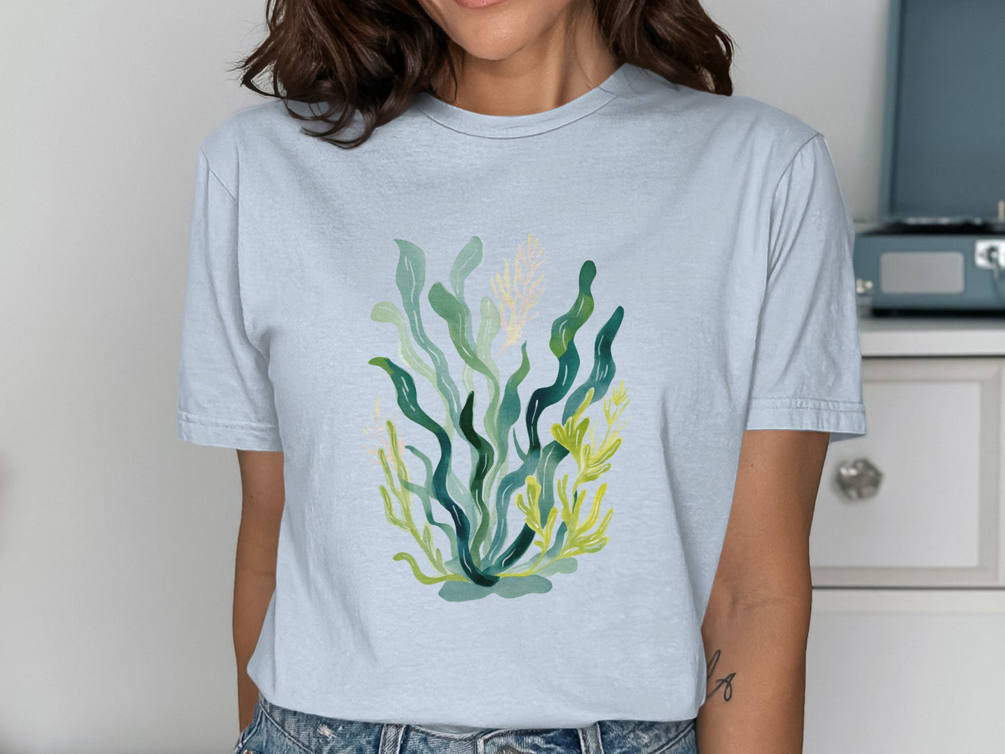 Light blue t-shirt with a green and yellow watercolor seaweed design.