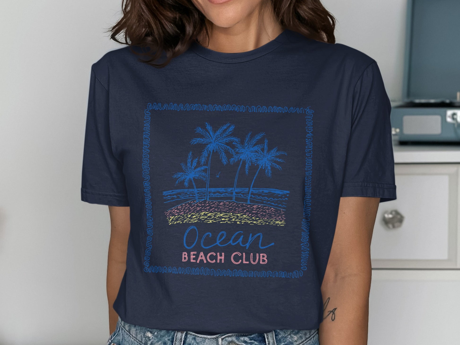 Dark blue t-shirt with "Ocean Beach Club" text and a stylized beach scene.