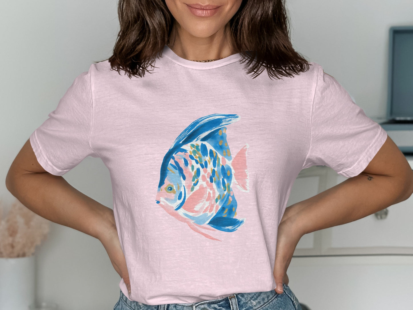 Light pink t-shirt with a watercolor-style fish illustration in blue, pink, and orange.