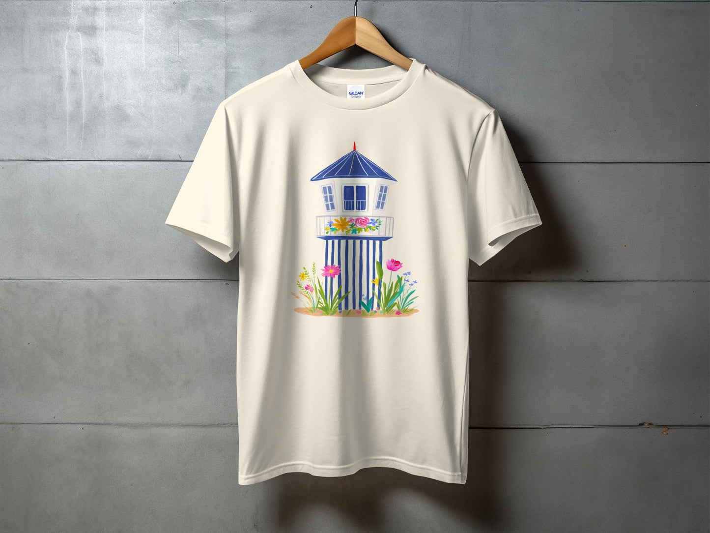 Cream t-shirt with a watercolor illustration of a beach lifeguard tower and flowers.