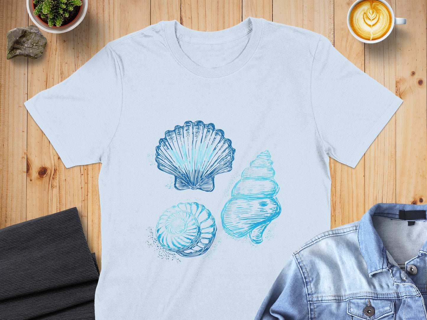 Light blue t-shirt with three sketched seashells in blue ink.