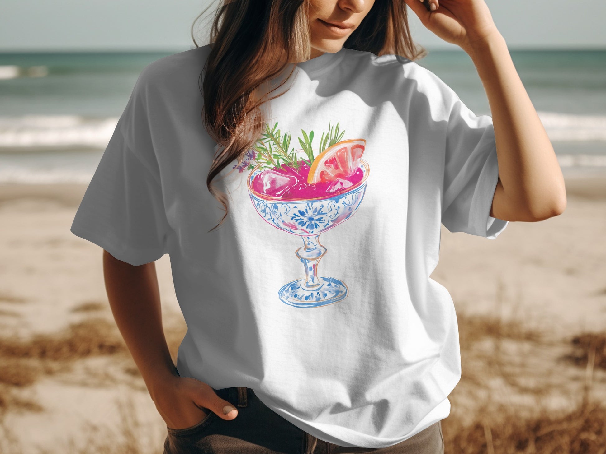 T-shirt with watercolor illustration of pink cocktail in glass with fruit and herbs.